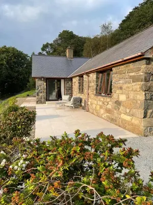 a stone house with a patio in front of it at Llety Cynnes in Machynlleth