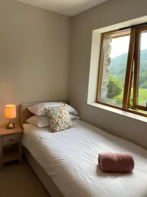 a bedroom with a bed with a pillow and a window at Llety Cynnes in Machynlleth