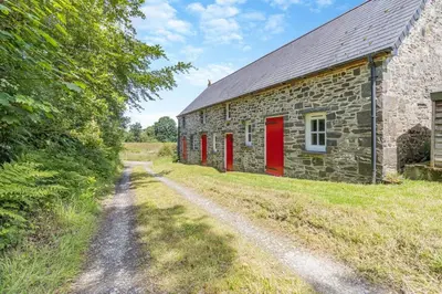 an old stone barn with red doors and a dirt road at 1 Bed in Llwynygroes oc-y29714 in Llangeitho