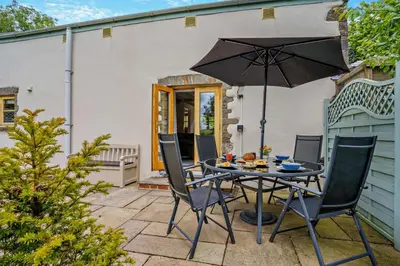 a table and chairs with an umbrella on a patio at 2 Bed in Crugybar oc-t29740 in Rhandirmwyn