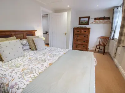 a bedroom with a large bed and a dresser at Moorhen Cottage in Ludlow