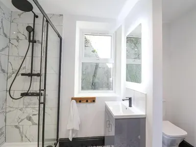a bathroom with a shower and a sink and a window at Gwynfa in Barmouth