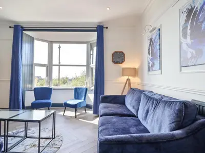 a living room with a blue couch and a table at Gwynfa in Barmouth