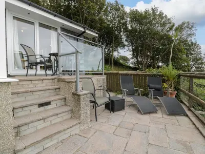 a patio with chairs and a table on a house at Woodland Roost in Barmouth