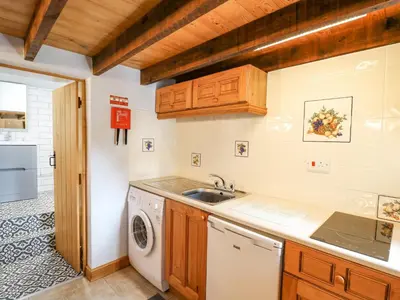 a kitchen with a sink and a washing machine at Ty Bach Twt in Llandysul