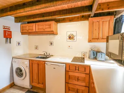 a kitchen with a sink and a washing machine at Ty Bach Twt in Llandysul