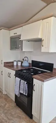 a kitchen with a black stove and white cabinets at Sea View Caravan - Aber Bay Holiday Park in Aberystwyth