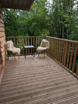 two chairs and a table on a wooden deck at Kestrel lodge in Wrexham