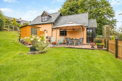 a house with a backyard with a table and an umbrella at 2 Bed in Devils Bridge oc-d29575 in Devils Bridge