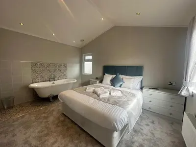 a bedroom with a bed and a bathtub and a bed and a bathtub at WH - Smugglers Lodge in Aberaeron