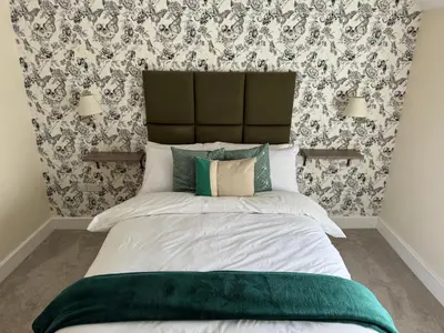 a bedroom with a large bed with a green headboard at Class Stays in Shrewsbury