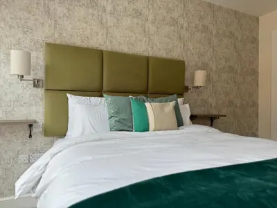 a large bed with a green headboard and pillows at Class Stays in Shrewsbury
