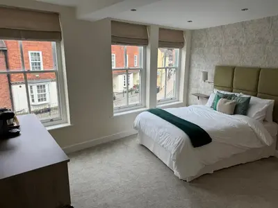 a bedroom with a large bed and two windows at Class Stays in Shrewsbury