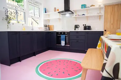 a kitchen with black cabinets and a pink floor at Trem y Don New Quay in New Quay