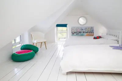 a white bedroom with two beds and a chair at Trem y Don New Quay in New Quay