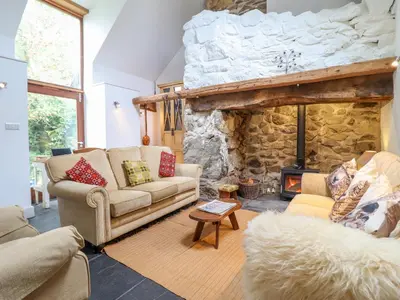 a living room with two couches and a stone fireplace at Ty Newydd Uchaf in Dolgellau