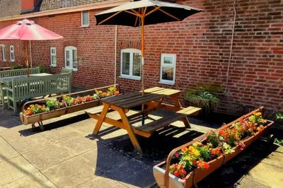 a picnic table and some flowers and an umbrella at The Boughton Peterchurch - Pub Grub & Bed in Peterchurch
