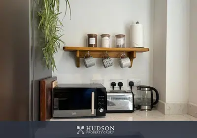 a kitchen with a counter with a microwave and a shelf at 3 Bedroom Modern Property with Parking in Shrewsbury
