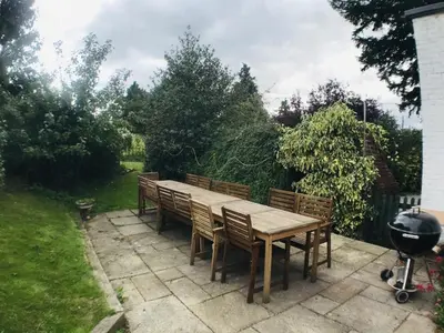 a wooden table with chairs and a grill in a backyard at RYTON GRANGE FARMHOUSE to sleep 12 in Shrewsbury