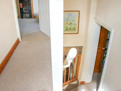 a stairway with a white chair and a hallway at Old Bricklayer's Arms in Bishops Castle