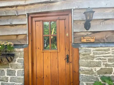 a wooden door on the side of a stone building at Tawny Owl Barn in Leintwardine