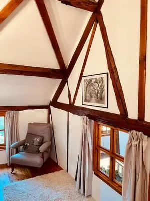 a attic room with a chair and a window at Tawny Owl Barn in Leintwardine