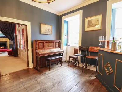 a living room with a piano and chairs in it at Llwynderw Hall in Llanwrtyd Wells