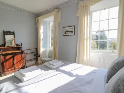 a bedroom with a white bed and a window at Llwynderw Hall in Llanwrtyd Wells