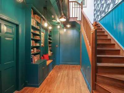 a hallway with blue walls and a staircase with bookshelves at Llwynderw Hall in Llanwrtyd Wells