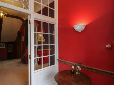 a red room with a table and a mirror at Llwynderw Hall in Llanwrtyd Wells