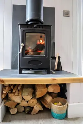 a stove sitting on top of a pile of wood at Nant Gwenyn - Hafan Hideaways Eryri in Llanymawddwy