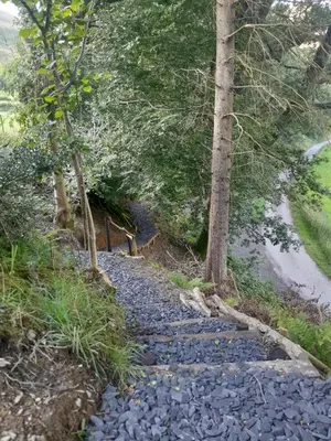 a stone path next to a river with trees at Nant Gwenyn - Hafan Hideaways Eryri in Llanymawddwy