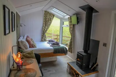 a bedroom with a bed and a stove in a room at Nant Gwenyn - Hafan Hideaways Eryri in Llanymawddwy