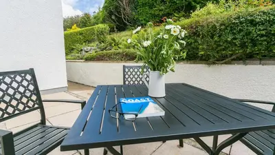 a blue picnic table with a vase of flowers and a book at Swn y Mor in Harlech
