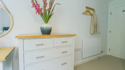 a white dresser with a vase on top of it at Swn y Mor in Harlech