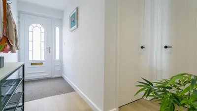 a hallway with white walls and a door and a plant at Swn y Mor in Harlech