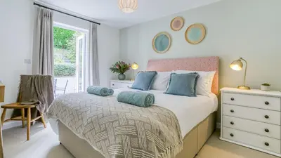 a bedroom with a bed with blue pillows and a window at Swn y Mor in Harlech