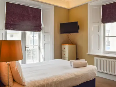 a bedroom with a bed with a television and windows at Uk47786 - Flat 4E in Aberystwyth