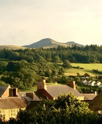 a view of a village with mountains in the background at Cosy Welsh Town Cottage in Brecon