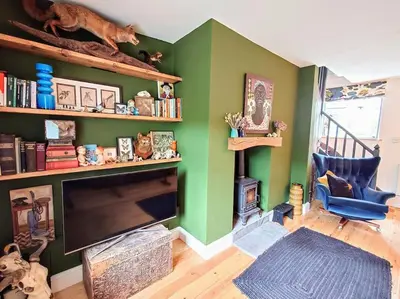 a living room with green walls and a flat screen tv at Cosy Welsh Town Cottage in Brecon