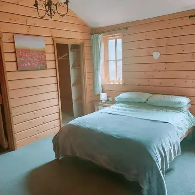 a bedroom with a bed in a wooden wall at Owl Cabin in Llanbrynmair
