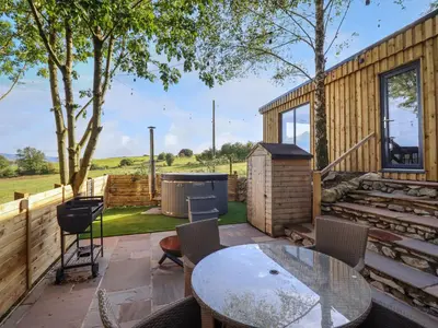 a patio with a table and chairs at Orchard Lodge in Corwen