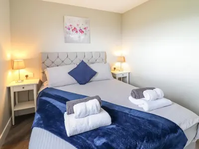 a bedroom with a large bed with towels on it at Orchard Lodge in Corwen