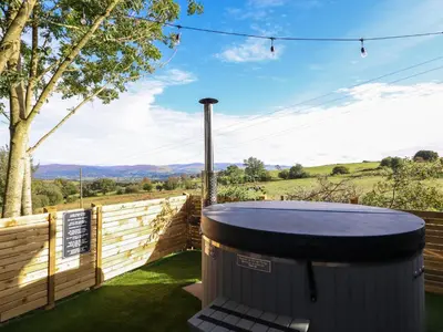 a hot tub in a yard with a fence at Orchard Lodge in Corwen