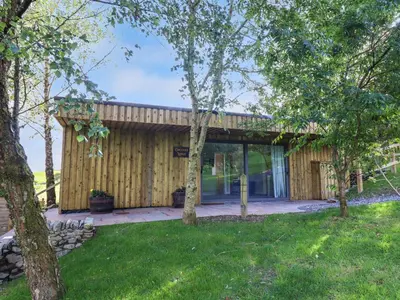 a wooden house with a patio in a yard at Orchard Lodge in Corwen