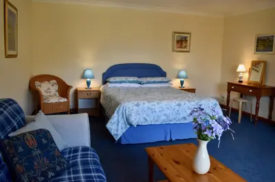 a bedroom with a bed and a vase of flowers on a table at Secluded Farmhouse with Private Lake in Llanwrda
