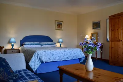 a bedroom with a bed and a vase of flowers on a table at Secluded Farmhouse with Private Lake in Llanwrda