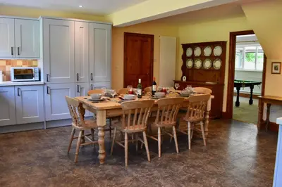 a kitchen with a wooden table and chairs in a room at Secluded Farmhouse with Private Lake in Llanwrda