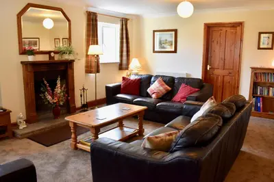 a living room with a leather couch and a coffee table at Secluded Farmhouse with Private Lake in Llanwrda