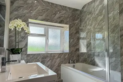 a bathroom with a tub and a sink and a window at Marrington Lodge in Chirbury